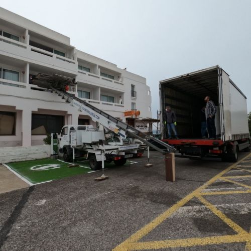 Vista amplia de la plataforma elevadora en posición junto al camión de mudanzas de Plataformas Ibiza
